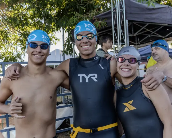 Trio de atletas abraçados na arena do evento