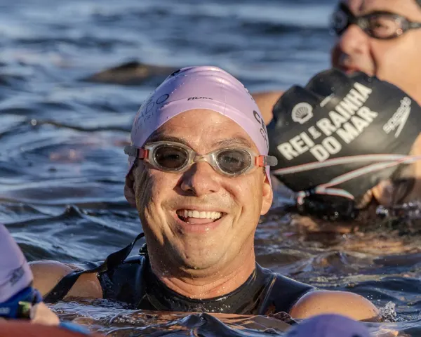Nadador sorridente na água com touca do evento
